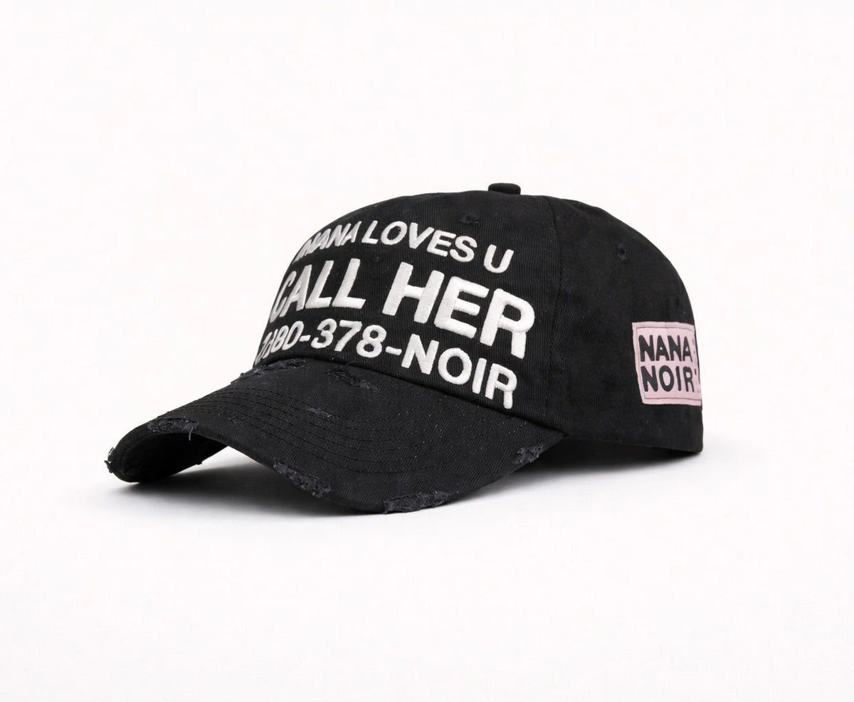 Angled side view of CALL HER distressed black dad cap with white embroidery and pink Nana Noir patch